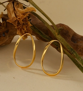 Gros plan de boucles d'oreilles ovales torsadées dorées sur un socle minimaliste