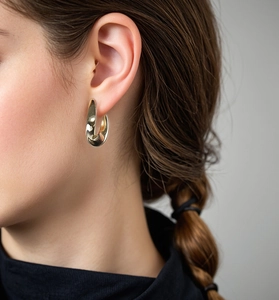 Close-up of a model wearing a polished gold U-shaped earring with minimalist curved design