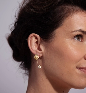 Détail de la boucle d'oreille dorée texturée et perle baroque sur le modèle