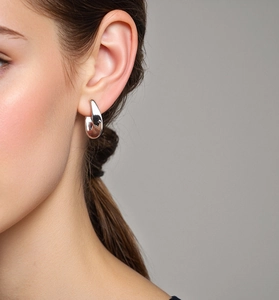 Close-up of polished S925 silver curved hoop earrings with a sculptural silhouette