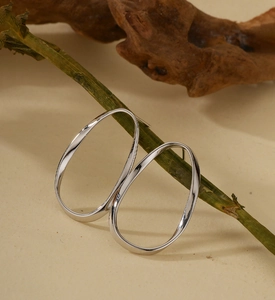 Détail de boucles d'oreilles créoles ovales torsadées en argent suspendues à une tige