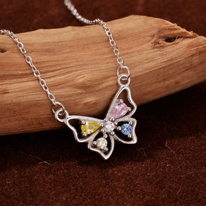 Collier papillon en argent S925 avec zircons colorés posé sur un support en bois