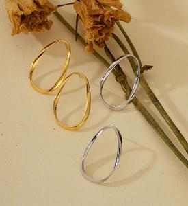 Boucles d'oreilles ovales irrégulières en or et argent sur un fond beige texturé