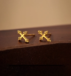 Detailed macro view of 18K gold plated S925 sterling silver cross earrings on wooden stand