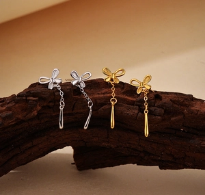 Macro shot of silver and 18K gold butterfly tassel earrings on a natural wood surface
