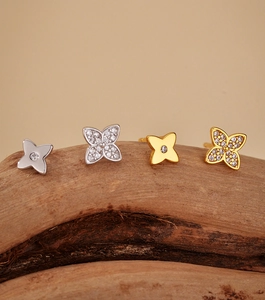 Macro detail of gold and silver clover stud earrings featuring zircon pavé settings