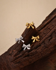 Détail des boucles d'oreilles nœud en argent S925 dorées et argentées sur bois
