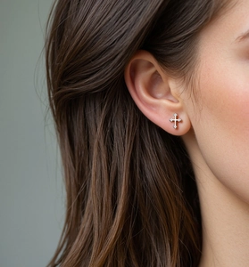 Close-up of S925 sterling silver cross stud earring with crystals on model ear
