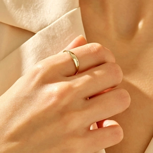 Minimalist high-polished golden ring shown on finger with elegant natural lighting