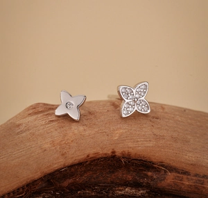 Macro detail of asymmetric clover earrings with polished finish and pavé cubic zirconia