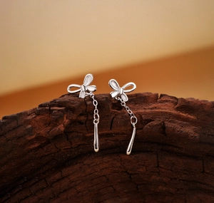 Macro view of S925 sterling silver butterfly earrings with droplet tassels on wood