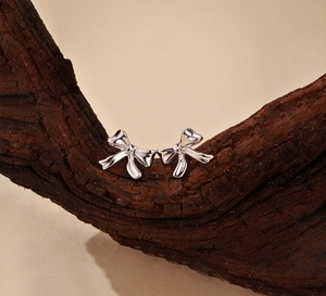 Vue macro des boucles d'oreilles nœud en argent sterling S925 sur socle en bois