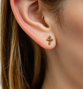 Macro shot of 18K gold plated S925 silver cross stud earring worn on earlobe
