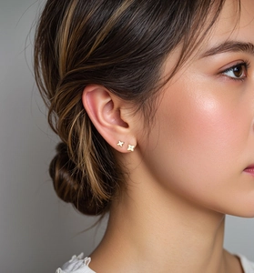 Detailed close-up of 18K gold plated clover and star studs with zircon on woman's ear