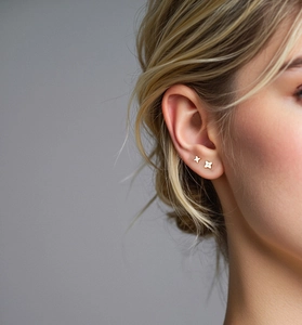 Close-up of minimalist 18K gold four-pointed star stud earrings with small diamond center