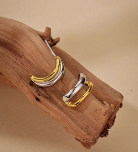 Détail de boucles d'oreilles nœud en C bicolores aux lignes métalliques or et argent