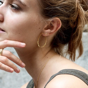 Boucles d'oreilles créoles ovales torsadées en argent S925 doré poli portées par modèle