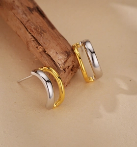 Gros plan de boucles d'oreilles créoles bicolores dorées et argentées en forme de C