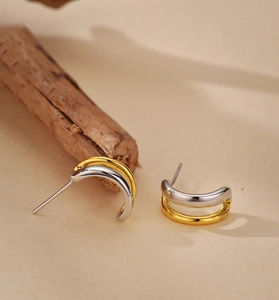 Gros plan détaillé de boucles d'oreilles créoles en forme de C bicolores en or 18 carats et argent