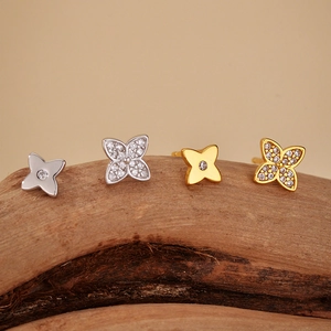 Elegant S925 silver and 18K gold clover earrings with diamonds on a natural wood surface