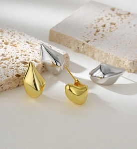 Detailed view of teardrop stud earrings in gold and silver finish on stone base