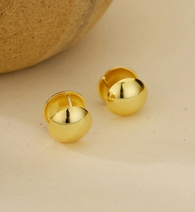 Gros plan sur les boucles d'oreilles boules dorées polies au fini miroir brillant