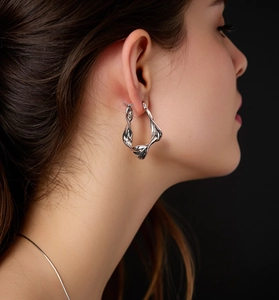 Dettaglio di orecchini a cerchio attorcigliati in argento sterling S925 su una modella