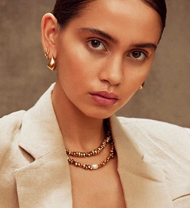 Detail of gold water drop earrings and layered pearl necklace on professional model