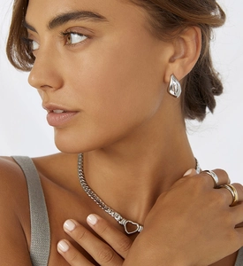 Detail of chunky teardrop earrings and layered chain necklace on model