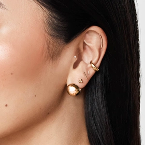 Parure de boucles d'oreilles dorées avec clous et manchettes sur un mannequin pour un look chic
