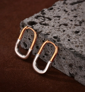 Detail view of two-tone S925 sterling silver U-shape hoop earrings on a rock