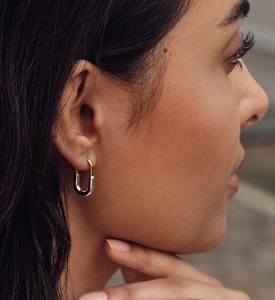 Detail of minimalist two-tone silver and gold U-shaped earrings worn by a model