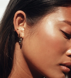 Close-up of 925 sterling silver gold-plated geometric U-shaped huggie earrings on ear