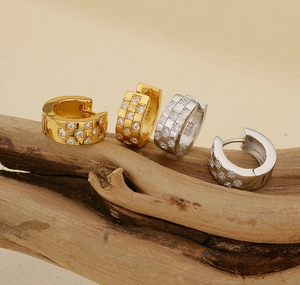 Detailed close-up of S925 sterling silver pave-set crystal huggie earrings on wood