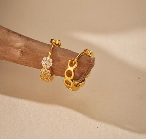 Dettaglio di orecchini a cerchio in argento 925 con micro-diamanti su un ramo di legno decor