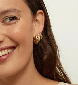 Détail de boucles d'oreilles en U dorées et pavées de zircons portées par un mannequin
