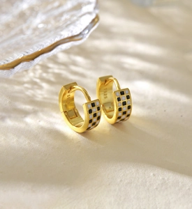 Détail des boucles d'oreilles créoles en argent S925 doré avec émail en damier noir et blanc