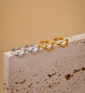 Dettaglio ravvicinato di orecchini a cuore traforati in oro e argento su pietra