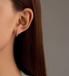 Gros plan d'une créole dorée avec des zircons rectangulaires portés par un mannequin femme
