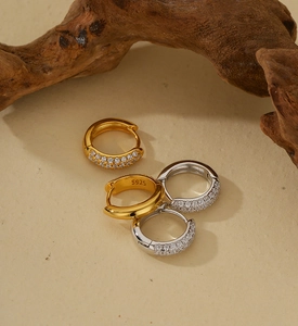 Macro shot of silver and gold S925 earrings with pave zircon on textured background