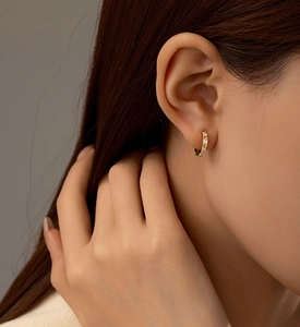 Gros plan sur une boucle d'oreille huggie dorée sertie de zircons carrés