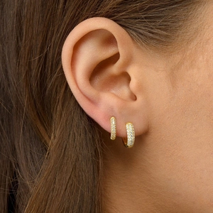 Close-up of gold-plated pavé crystal hoop earrings set on a model ear lobe
