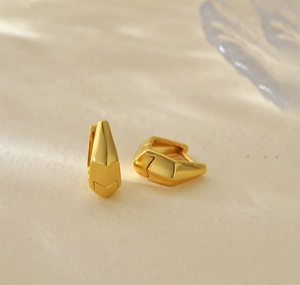 Close-up of minimalist gold S925 silver geometric hoop earrings with polished facets