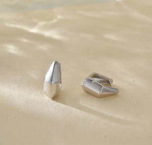 Macro detail of geometric S925 sterling silver earrings with polished minimalist finish