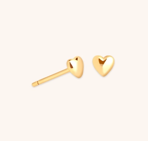 Close-up of polished golden heart stud earrings with a 3D minimalist design and glossy finish