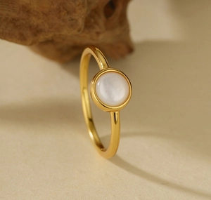 Detail of elegant gold-plated 925 silver ring with white shell stone on matte stand