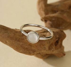 Detailed view of an elegant 925 silver ring with a white shell stone on natural wood