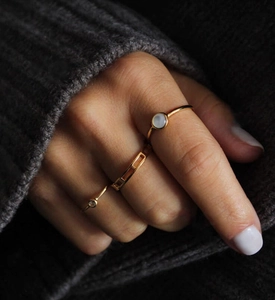 Close-up of a three-piece gold ring set with white shell stone and geometric hollow design