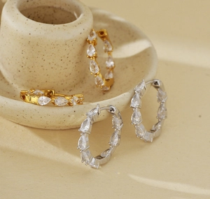Macro shot of S925 sterling silver hoop earrings with pear-cut zirconia in gold and silver