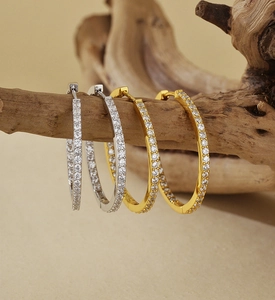 Detail of silver and gold S925 sterling silver hoop earrings with pavé crystals on wood